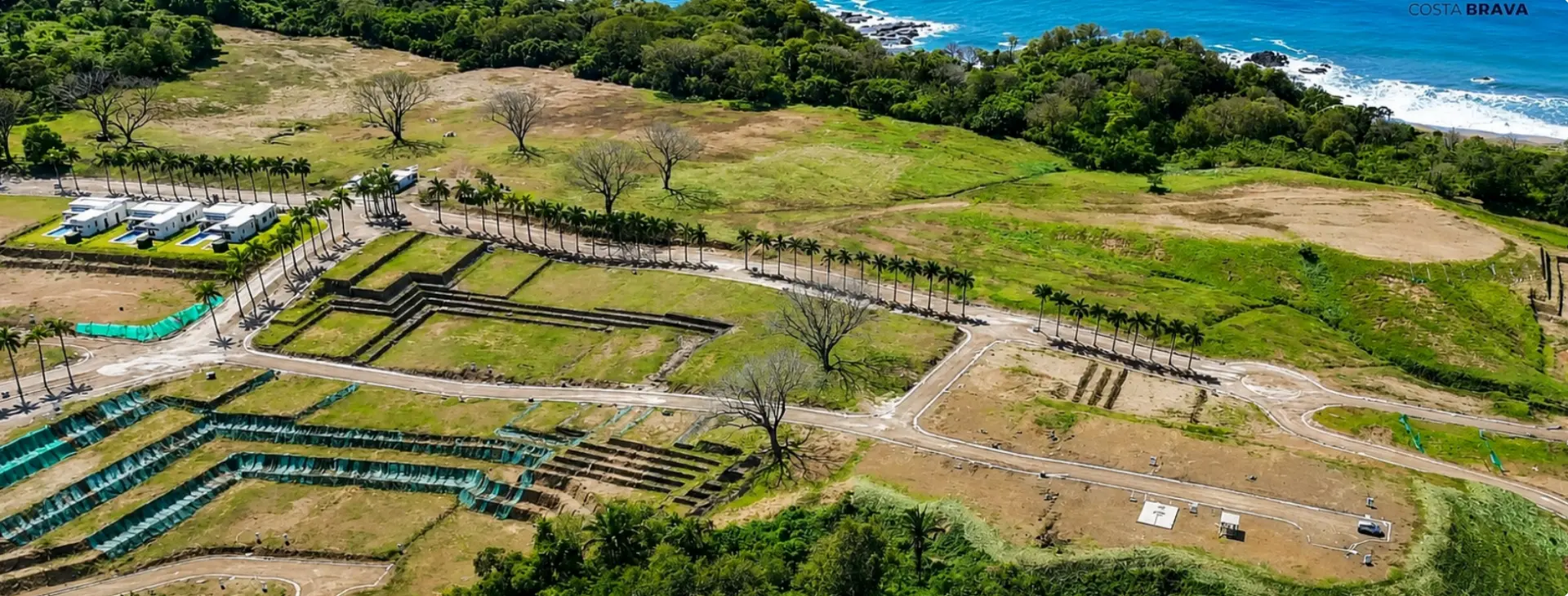 Wide aerial panorama of the Costa Brava site showing developed lots, roads and the Pacific shoreline
