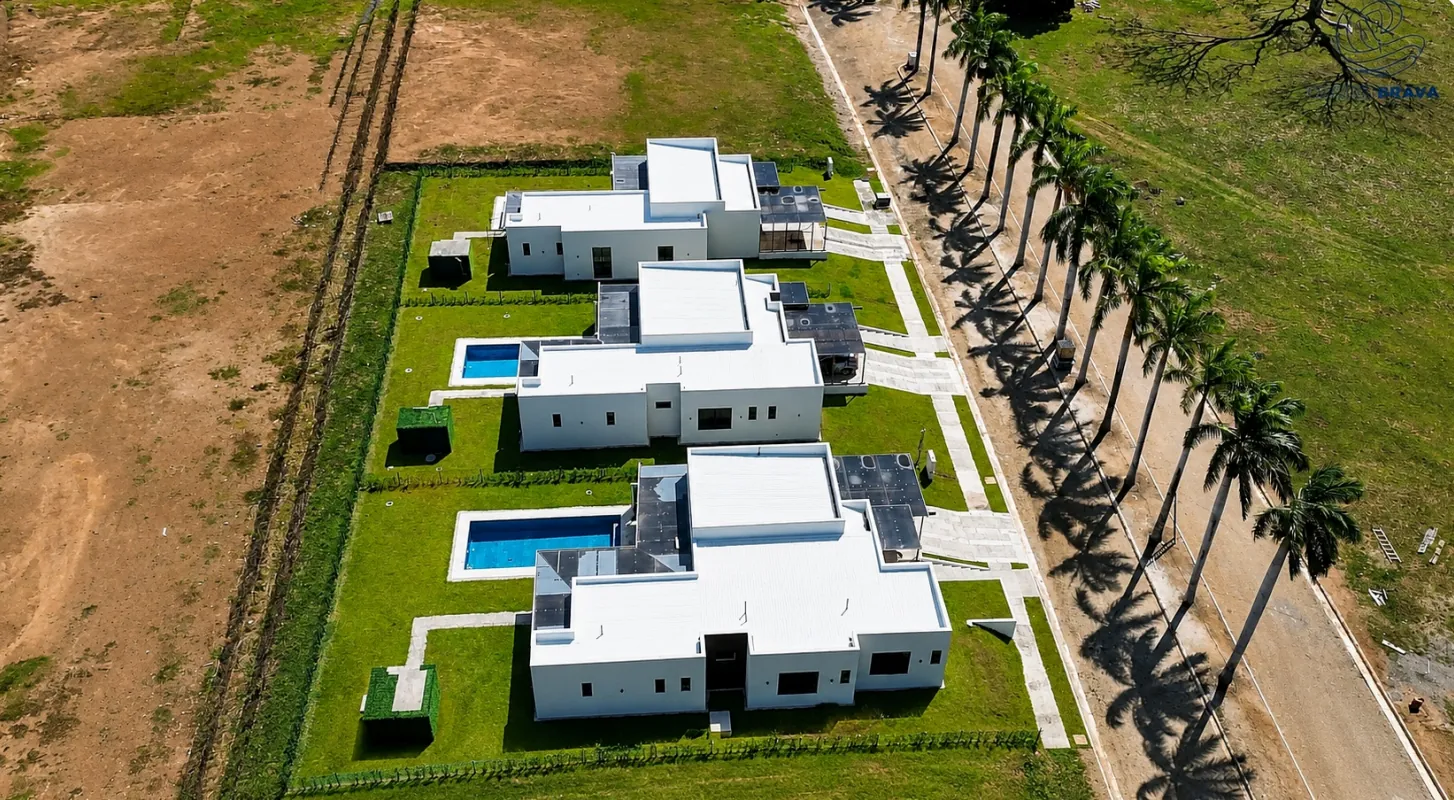 Aerial view of three completed villas with private pools and palm-lined street